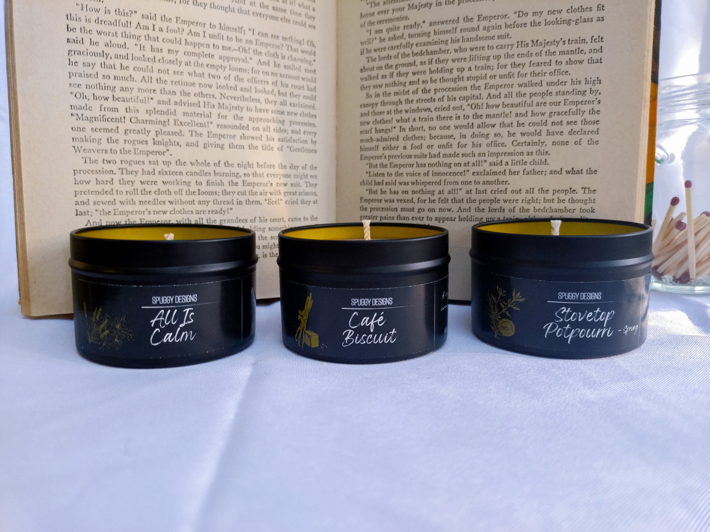 Three soy candles with labels in front of an open book