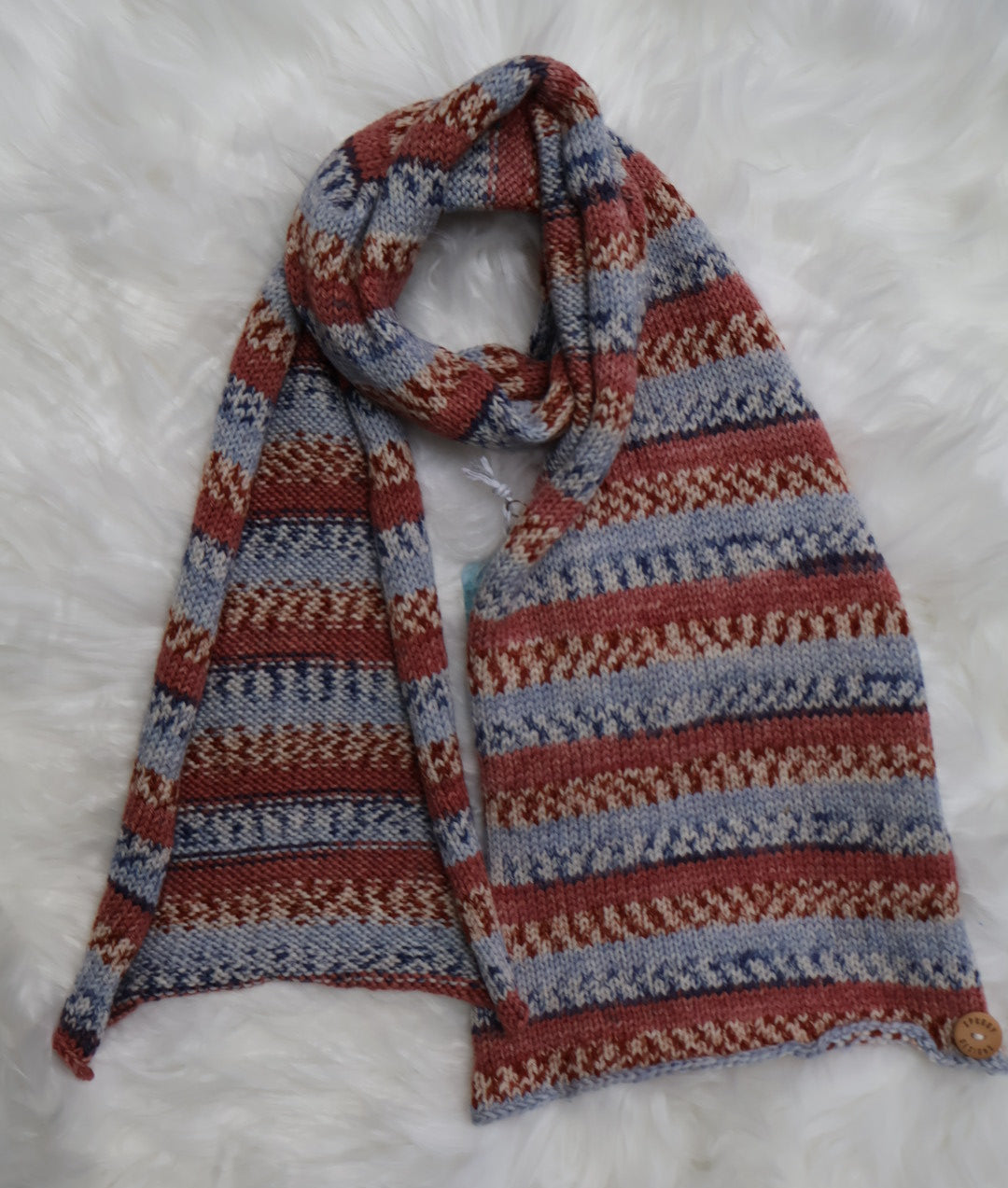 Knitted scarf with a pattern on a white fluffy surface